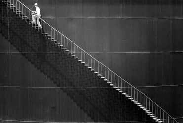 Man climbs steps on side of an oil storage tank