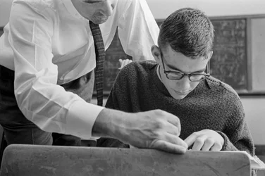 Teacher helping student with text at James A. Garfield High School