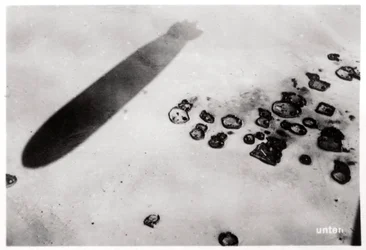 Aerial view of a desert settlement, with a shadow cast by a Zeppelin