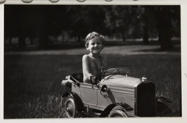 Boy driving a toy pedal car, c 1930