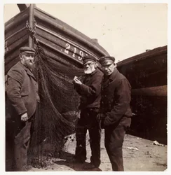 Fishermen standing by a net, c 1905