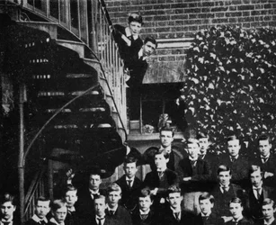 Winston climbing a staircase, while the class pose, c1889
