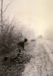 A Country Road Wrapped in Morning Mists with a Man Splitting Stones in the Foreground