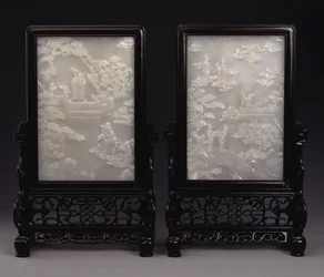 A pair of white jade table screens carved in relief with immortals amid clouds or in gardens with attendants and mythical beasts