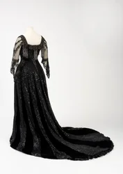 Black full-length evening gown worn by Queen Alexandra, with bead and sequin decoration and incorporating Queen Alexandra’s signature black silk and gold-lettered name tape, made by Barolet of Knightsbridge, London, 1908-1910 (silk & velvet)