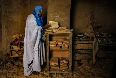 Man flips through a priceless manuscript in his sandy house, 2009