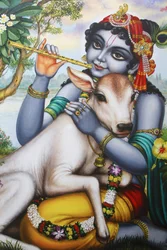 Hindu god Krishna playing a flute and fondling a calf, India