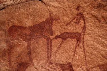 Rock art, Prehistory: Rock painting of a cow, calf and character in an ornate shelter, in the Uweinat massif, Egypt