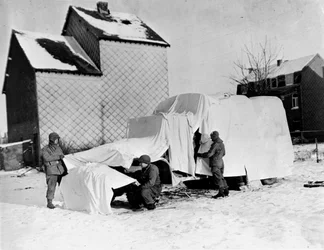 Second World War: Near Bastogne (Belgium) at the end of December 1944: American soldiers use white sheets to conceal a truck from the enemy