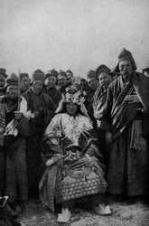 Tibet. Magician in full dress and an admiring band of monks. 1920