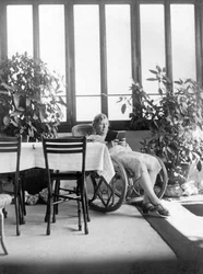 Woman sitting in a rocking chair, reading a book. 1915 approx. Germany