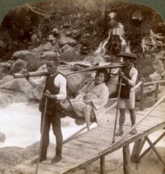 Japanese woman in a yamakago mountain chair crossing the torrential Daiya river near Nikko, Japan
