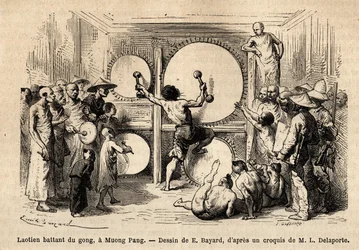 A Laotian beating gong in Muong Phang, weapon of several hammers, and striking with double blows on several instruments placed in front of him; the author of the story is represented in the audience, carrying his cardboard drawing under his arm. Engraving