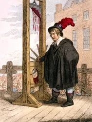 George Tierney dressed as an executioner standing next to a guillotine