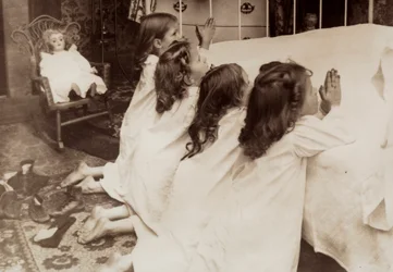 Four little girls kneeling at the side of a bed as they say their evening prayer