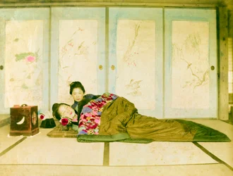 Reclining on a Futon. Two Japanese Women Recline on a Traditional Futon Placed on the Floor. Japan, circa 1910.