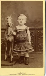 Young girl standing by rocking horse