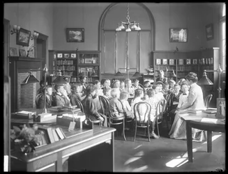 Children listen to a woman in the reading room of an unidentified branch of the Queens Borough Public Library