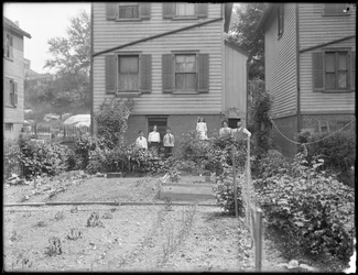 Family poses beside their backyard vegetable garden, Inwood, New York, c.1910