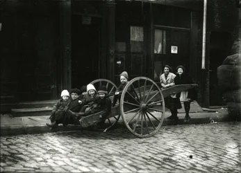 Group of children in cart, with girl and woman standing behind