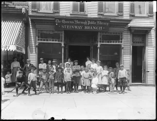 Group portrait of children in front of the Steinway branch of the Queens Borough Public Library