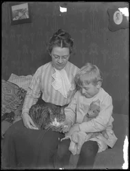 Harriet E. Hassler and William Gray Hassler, seated with tabby cat (Reddy) and teddy bear, c.1911