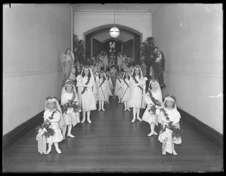 Little girls at the Roman Catholic Orphan Asylum, Kingsbridge, Bronx, coming back from chapel in white dresses with wreathes and garlands, October 20, 1914