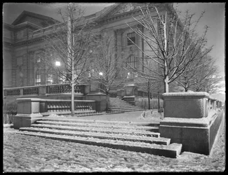 Night view of the northeast corner of the steps outside the main branch of the New York Public Library in the snow, 42nd Street and Fifth Avenue, New York City