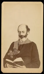 Unidentified balding, bearded man reading while seated